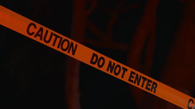 Police do not enter tape at night with red and blue flashing lights close up demonstrates restricted access site security and tense incident atmosphere with focus on warning message