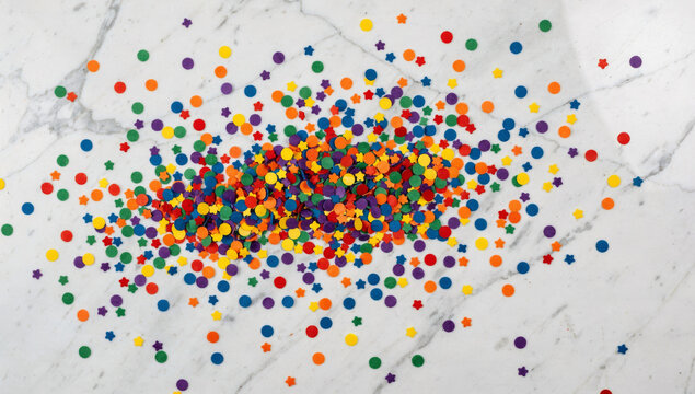 Confetti rainbow colors scattered on white marble, celebration