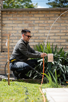 Man watering garden plants with water hose
