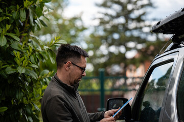 Man inspecting paperwork on car in outdoor setting © Zoran Jesic