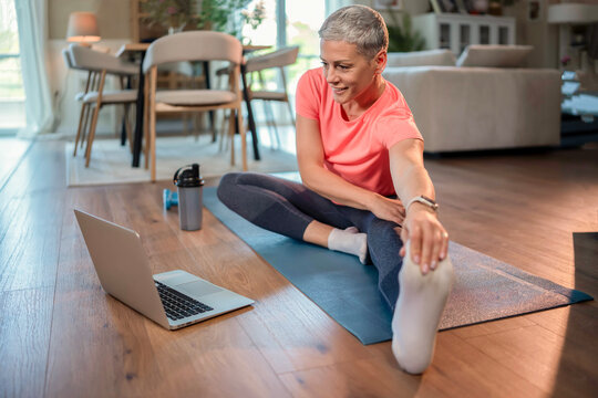 Mature woman stretching watching online exercise class