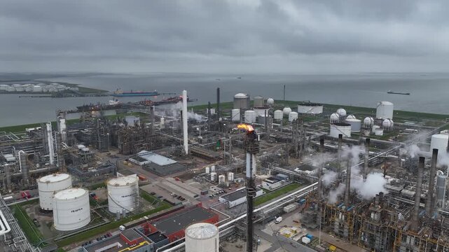 Aerial view of a chemical plant at sunset. Drone shot. Curling fire and cumin smoke filling the sky. Smoking chimneys from the factory. Chimneys of an oil refinery at sunrise pollute the environment