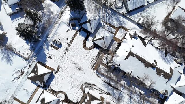 Aerial perspective reveals snow-laden houses and leafless trees