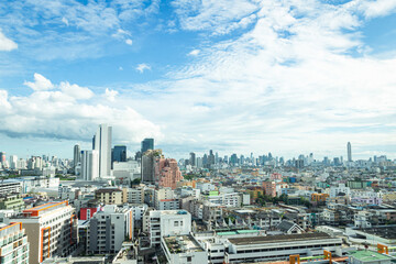 Naklejka premium Panoramic city skyline with modern skyscrapers and residential buildings under a bright blue sky with white clouds