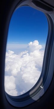 plane window view, clouds, blue sky, fluffy white puffs, soft, fluffy