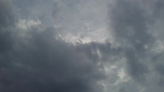 Overcast sky with dark hues. Dense gray clouds with textured layers and subdued light rays. Heavily textured overcast sky with deep gray tones and brooding seascape background