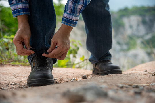Close-up man hands tie up shoes for footwear concept. Close up shot of man hands tied shoestring for his brown construction boots. Man hands tie shoes for footwear concept. kneels down rope outdoors