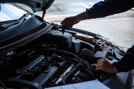 Close up Mechanic man hands repairing car auto repair shop uses jack change tyre. Open vehicle hood checking up auto mobile. Man hands fixing Shock absorber machinery vehicle mechanical service