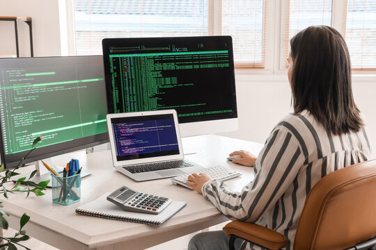Female programmer working at desk in office, back view
