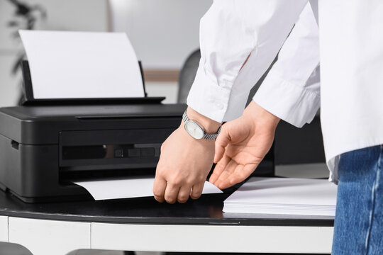 Businesswoman using printer on desk in office, closeup