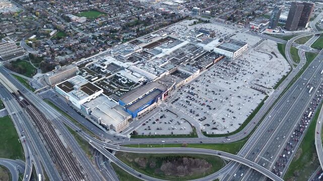 A cinematic 360-degree aerial drone orbit over Yorkdale Shopping Centre at night, showcasing the illuminated luxury mall, transit-oriented infrastructure, and heavy traffic on Highway 401