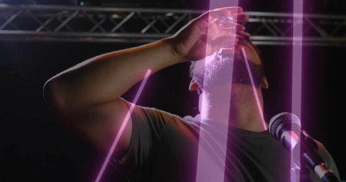 Male performer addressing mic, drinking shot, reacting, raising arm, neon-pink streaks hyping crowd
