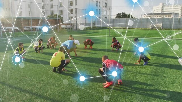Coach leading low-squat drill, team mirroring for soccer warmup as node overlay rising above group