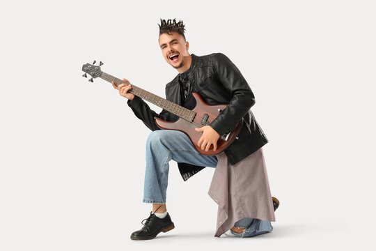 Cool young man with dreadlocks playing guitar on white background