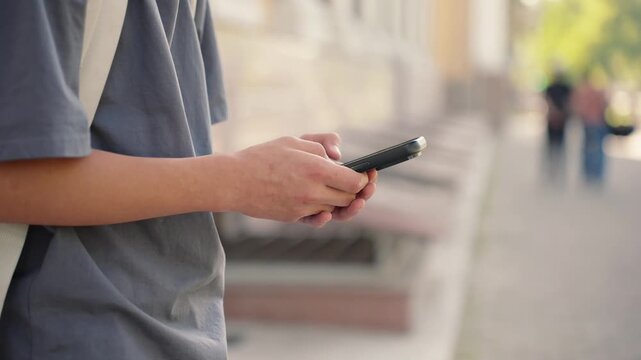 Close up of hands using smartphone while walking outdoors. Real people, authentic digital lifestyle and communication concept.