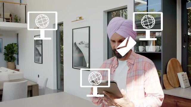 Man tapping tablet at island, causing monitor and envelope icons indicating tech communication