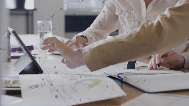 Women starting biz review tapping tablet marking charts noting and using phone overlay linking data
