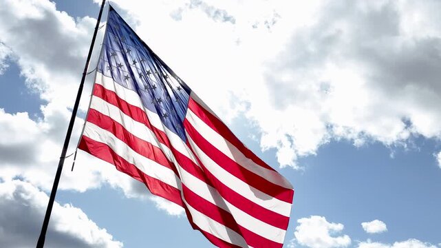 American Flag Waving in the Wind Against a Blue Sky with Clouds