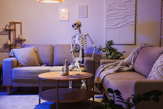 Human skeleton model sitting on sofa in living room at night