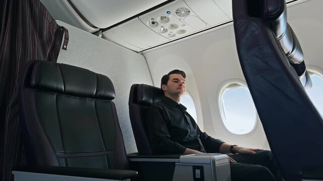 Businessman on Commercial Plane Flight Pressing Call Button