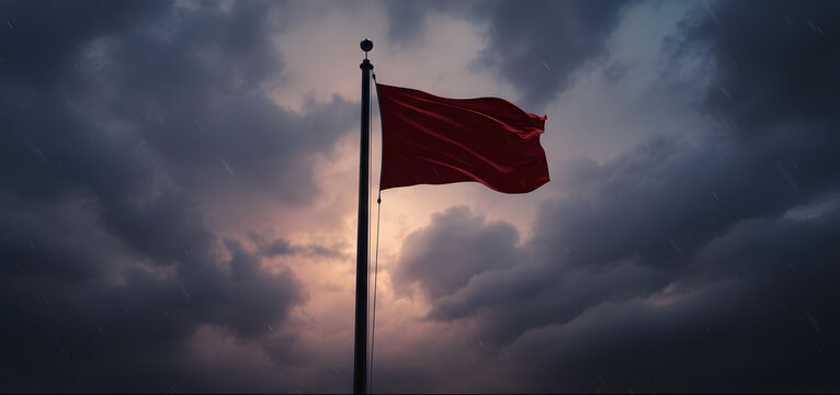 Red flag waving on a tall pole under a stormy sky