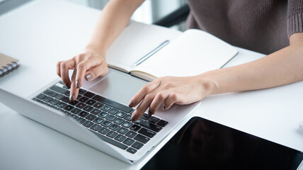 Fototapeta premium Close up, business woman working on laptop with notebook and digital tablet on office desk