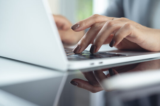 Close up of business woman working, typing on laptop keyboard, surfing the net on office desk.