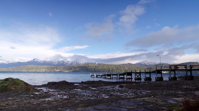 Pier Overlooking Nahuel Huapi Lake with Snow-Capped Mountains and Argentine Flag in Patagonia