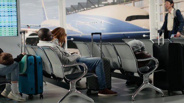Jet lagged passengers sleeping in airport during air transport congestion causing delayed flights. Multiethnic people napping on chairs in lounge during holiday trip, waiting for another plane