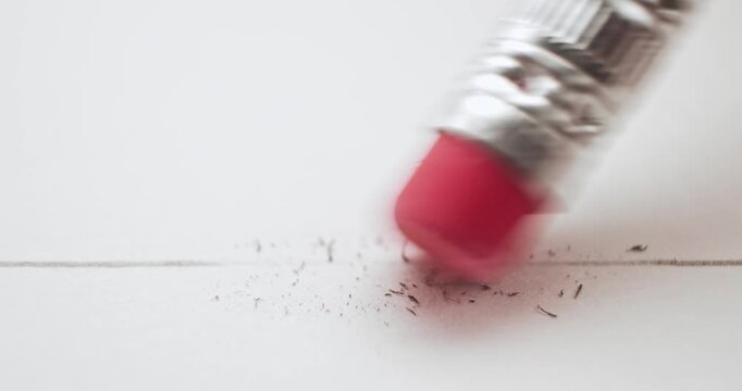 Erasing a pencil line with a pink eraser and creating a mess on white paper. Conceptual bad idea, fixing problems, failure or mistake, wrong decision, or to remove an error. Back to School supplies.