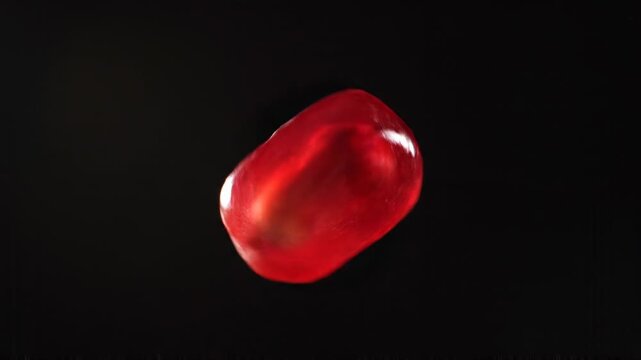 Single Red Pomegranate Seed Spinning On Black Background