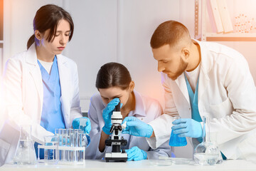 Scientists with microscope studying samples in laboratory © Pixel-Shot