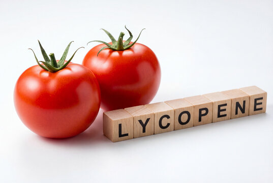 Two fresh red tomatoes with wooden blocks spelling lycopene, a healthy antioxidant nutrient