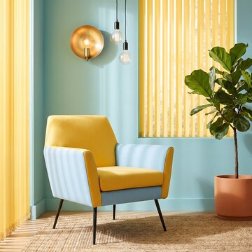 Modern living room corner featuring stylish yellow and blue armchair with lush fiddle leaf fig plant and gold wall lamp against soft pastel blue wall