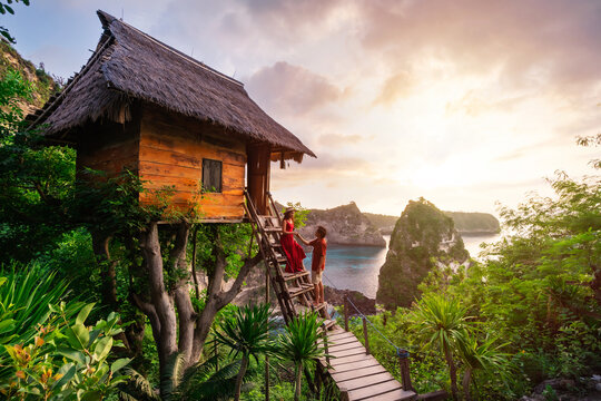 Young couple traveler enjoying and looking beautiful sunrise at the tree house in Nusa Penida island Bali, Indonesia