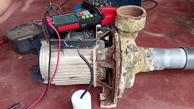 Technician Testing the Capacitance Value of a Motor Condenser Using a Digital Clamp Meter