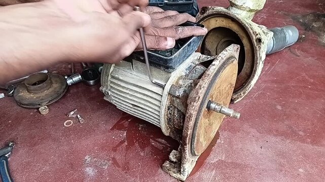 Technician Using an Allen Key to Unscrew Bolts from the Front End Plate of an Electric Motor