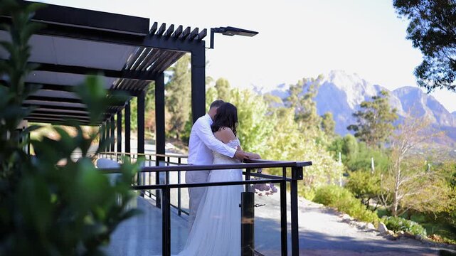 Young bride and groom stand at on venue deck overlooking mtn scene