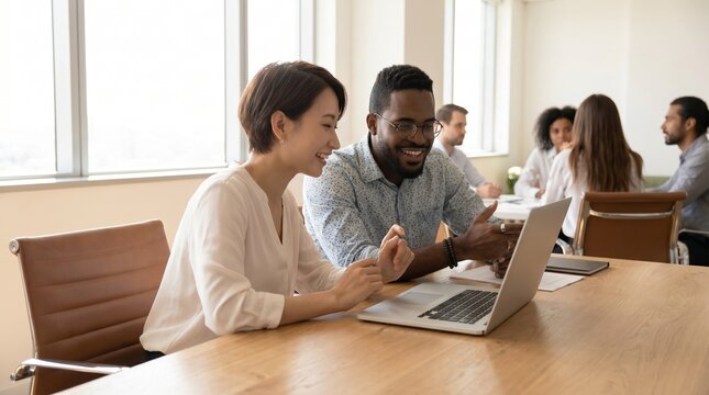 Diverse Team Collaborating on Laptop in Bright Conference Room.