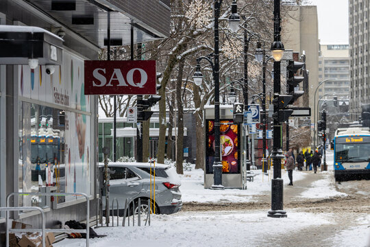 Canada, Montreal, 25 December 2025 : Snowy street scene with people walking near SAQ store