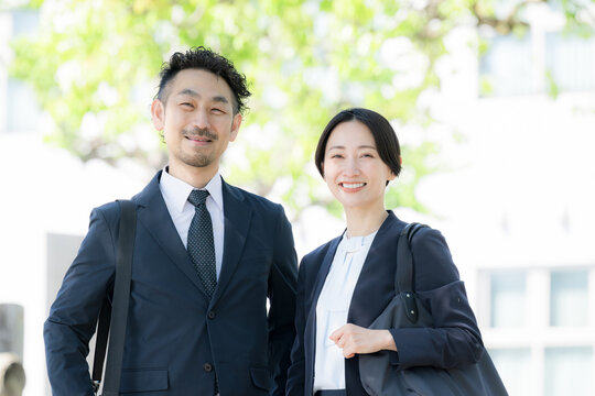 新緑の中屋外のビルの前で笑顔のビジネス男女のポートレート　上司や信頼とキャリアイメージカメラ目線笑顔