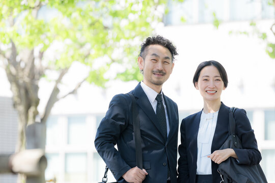 新緑の中屋外のビルの前で笑顔のビジネス男女のポートレート　上司や信頼とキャリアイメージカメラ目線笑顔