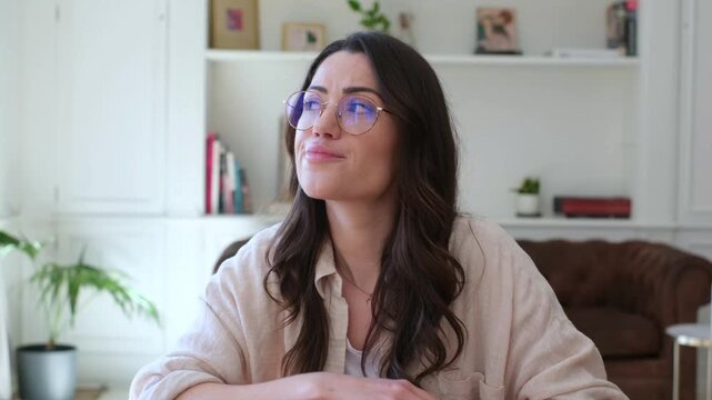 A young woman with glasses appears thoughtful and pensive, then shows signs of boredom or frustration while working or studying from home. Her expression shifts from contemplation to weariness.