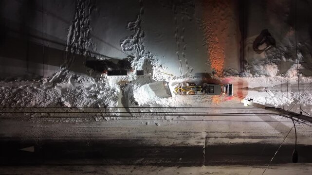 Aerial drone view of a large snowplow pushing heavy snow from streets in Beechville, Halifax area after blizzard. Nova Scotia, Canada, overnight winter maintenance on suburban roads 4K.