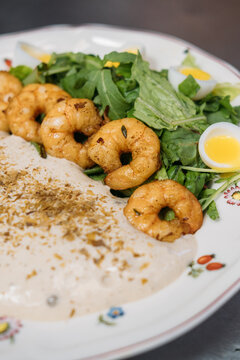 Healthy appetizer. Tasty salad. Delicious meal with grilled crunchy prawn row on greens garnish quail egg plated with whipped sauce.