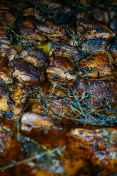 Spicy dish. Barbecue food. Rows of chicken thighs on tray with thyme sprig. Appetizing fat grilled dish for catering restaurant service.