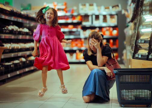 Exasperated Mom Dealing with a Loud Kind in a Supermarket. Stressed mother feeling embarrassed by her hyperactive daughter in grocery store