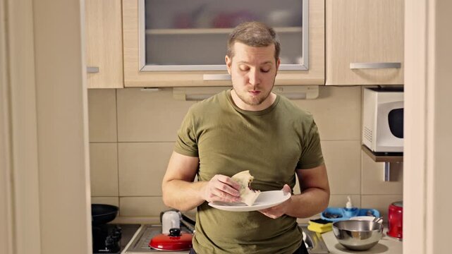 A casual moment captured in a modern kitchen as a man enjoys a quick and simple meal.