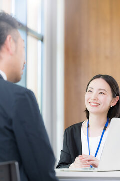 綺麗なオフィスで法人営業でヒアリングしながら提案(プレゼン)する若い女性社員のポートレート信頼と商談　保険や企画の提案などのイメージ