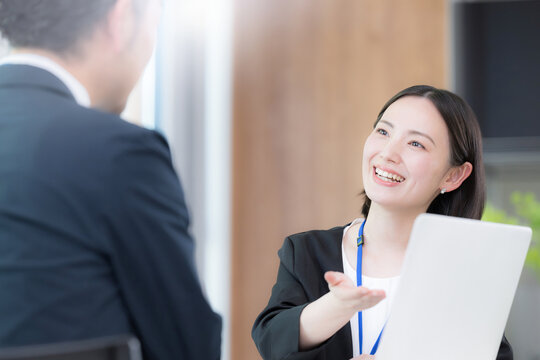 綺麗なオフィスで法人営業でヒアリングしながら提案(プレゼン)する若い女性社員のポートレート信頼と商談　保険や企画の提案などのイメージ